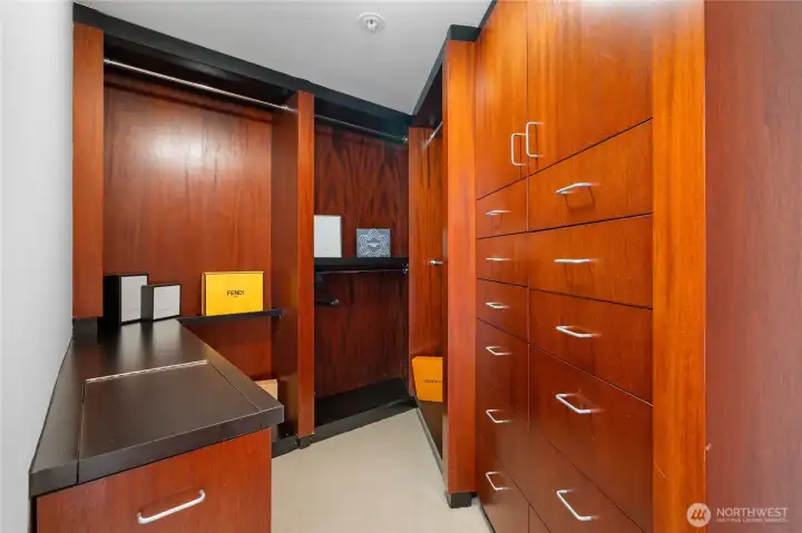 Custom, walk in closet features dedicated built in hamper.