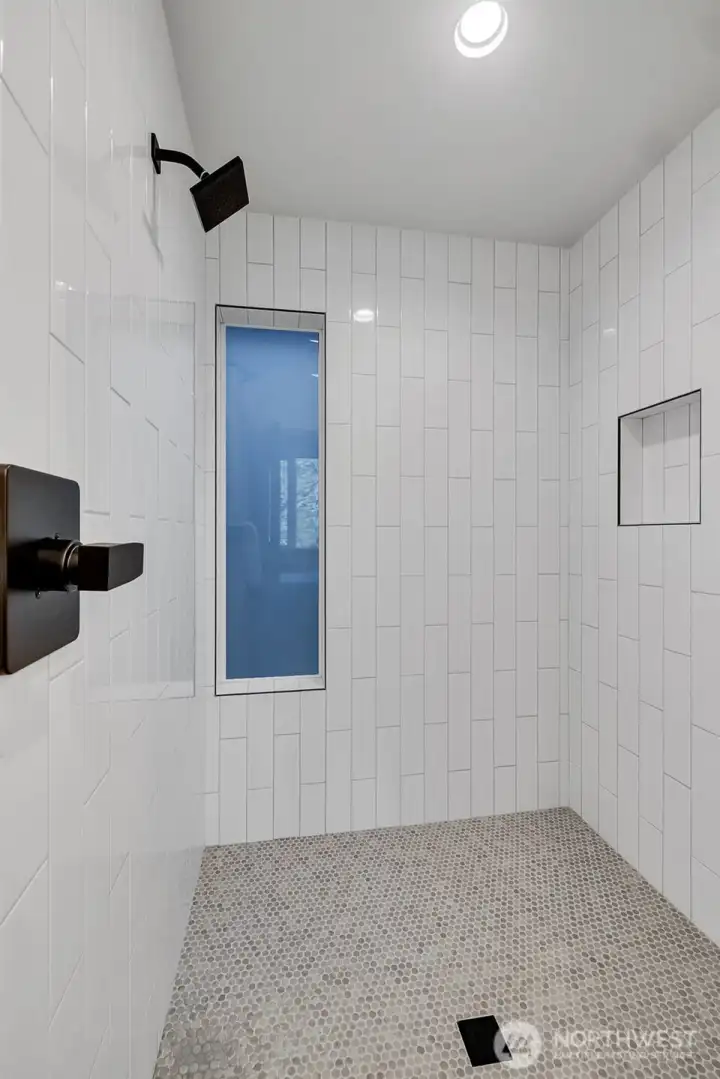 Penny tiled shower floor, subway tiled walls and black-matte fixtures showcase the thoughtful design that runs seamlessly through the primary ensuite.