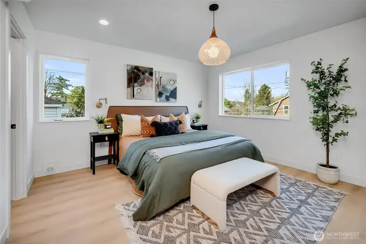Custom stylish lighting and wall sconces add elevated touches to the spacious primary bedroom.