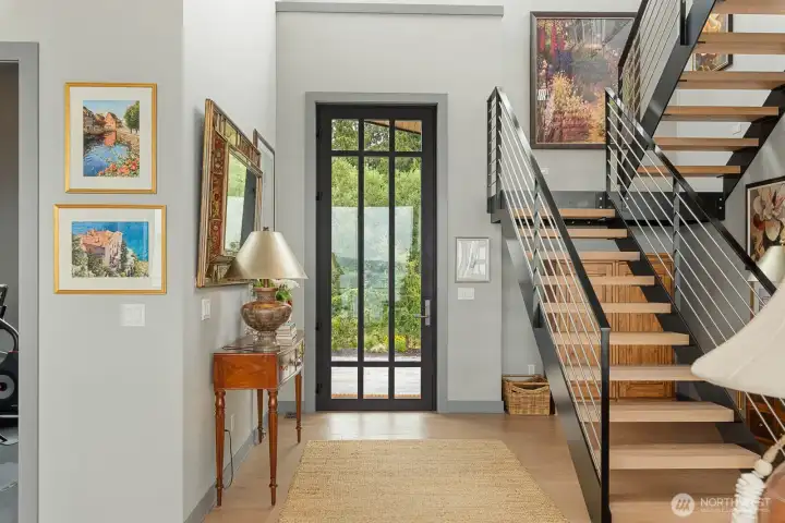 A sculptural open-metal staircase with solid wood treads, precisely matched to the French Oak flooring, creates a striking architectural focal point upon entry.
