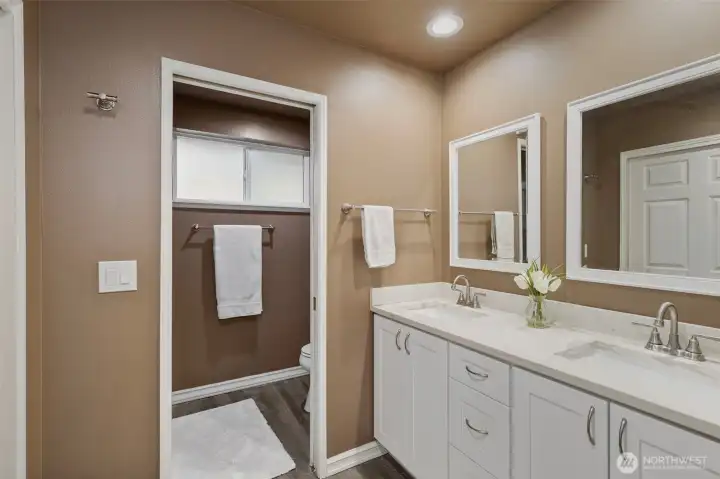 The primary enjoys a stunning 3/4 bath, with double vanities topped by quartz counters, large shower through the open doorway, and a huge closet on the right.