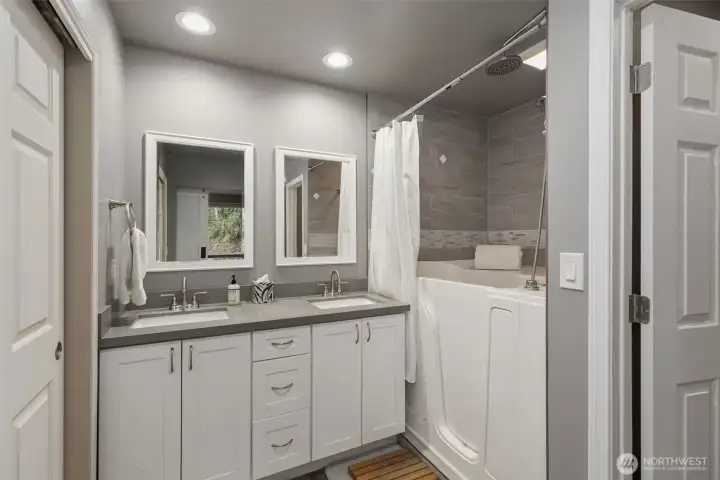 This beautifully updated full bath connected to the second main-floor bedroom features a convenient walk-in tub with overhead shower and tiled surround. Double vanities and large closet on the right complete this spa-like space.
