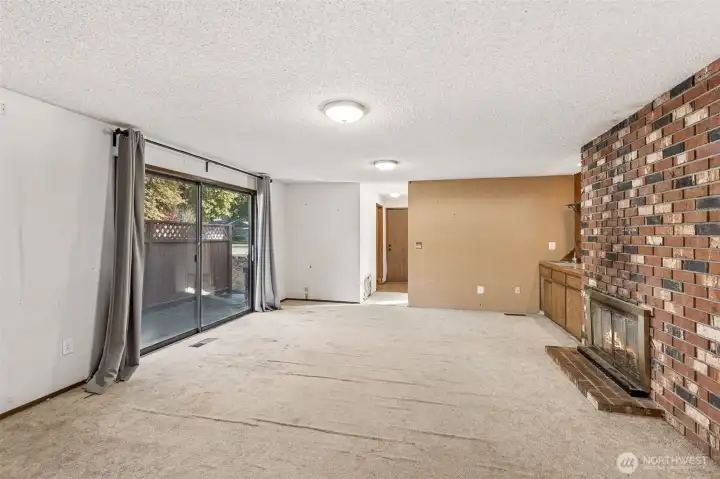 View of family room from kitchen, patio doors to your right lead to your patio, double-sided natural fireplace to your right. Straight ahead is your utility room, another bedroom and garage entrance.