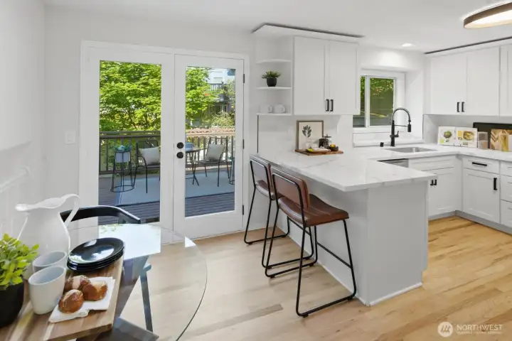 Second eating area plus double doors leading to an expansive deck overlooking a peaceful backyard with mature landscaping
