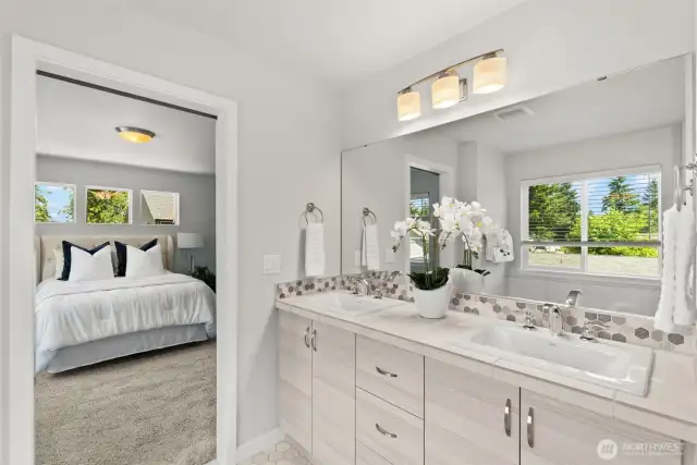 In the primary bathroom, a dual-sink vanity is complemented by designer selected decorative tile backsplash.
