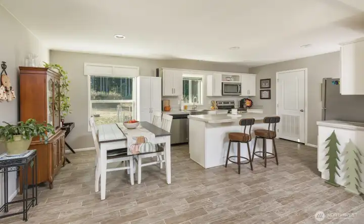 The dining area sits beside a large picture window, filling the space with natural light and scenic views of the surrounding property.