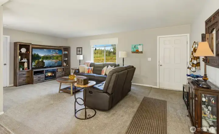 The spacious living room features plush carpet, abundant natural light, and an open layout perfect for entertaining or relaxing.