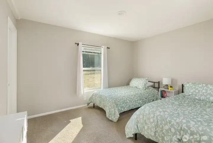 A comfortable bedroom with soft carpet, large window, walk-in closet, and neutral colors ready for personal touches.