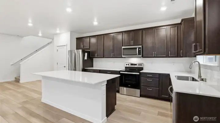 Bright, modern kitchen featuring quartz countertops, stainless steel appliances, and extensive cabinet storage.