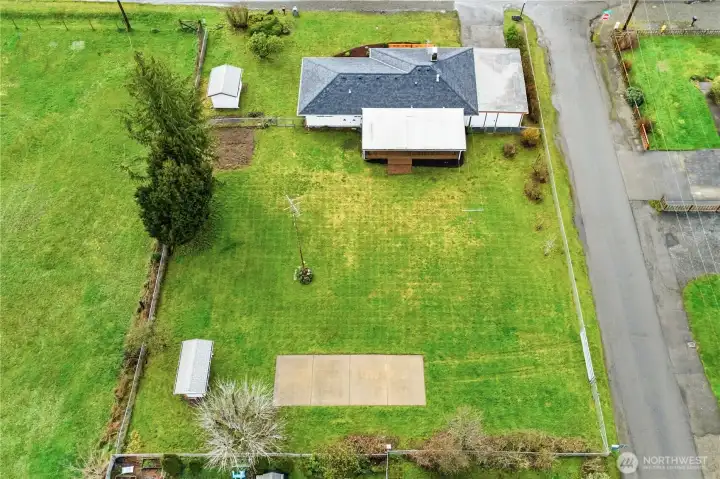 This aerial view shows off the backyard of the home, the size of the cement slab, and the layout of the property.