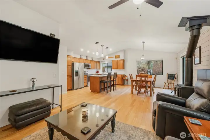 Inviting living room with warm bamboo flooring and a cozy wood stove, creating a comfortable space to relax within the home’s open-concept design.