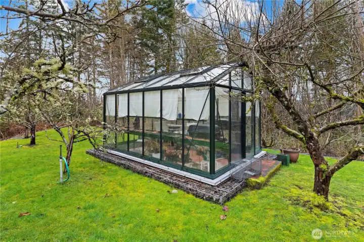 Greenhouse sits next to raised garden beds on this 1.2+ acre lot