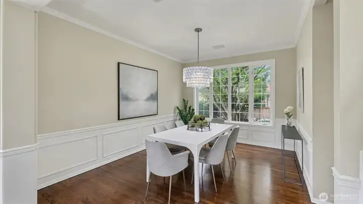 Formal dining area features elegant crown molding, wainscot detailing, and views of the private backyard.