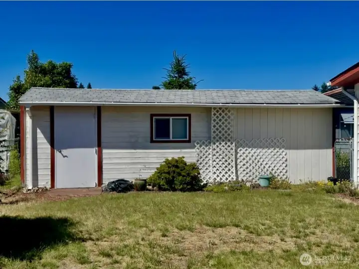 Garden shed door on left and Hobby Shed on right with a gate to the carport