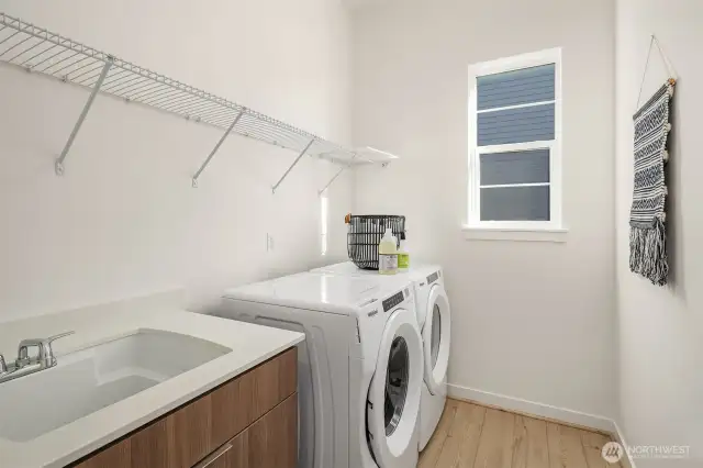 Laundry room includes cabinet with sink, washer & dryer
