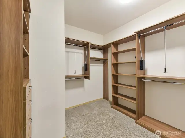 Primary attached closet with shelving and built-in drawers.