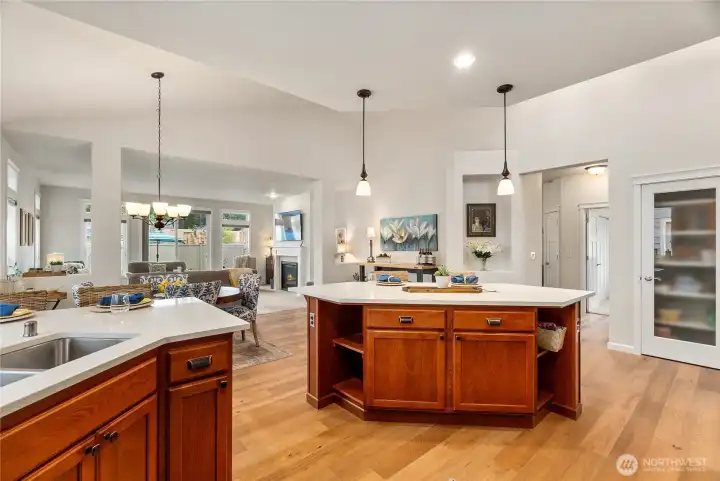 A large quartz topped island with bar seating anchors the space and provides additional storage. Vaulted ceilings and rich engineered hardwood floors enhance the sense of openness