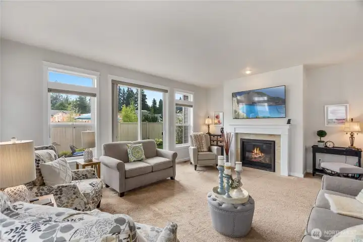 This light-filled living room offers a perfect blend of warmth and style. A gas fireplace with a tile surround and crisp white mantel serves as a focal point, And the TV above the fireplace stays with the home!