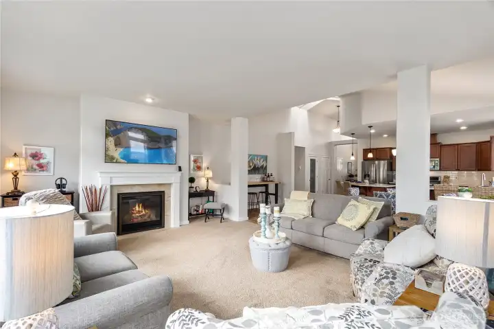 Plush carpeting and soft neutral tones create a cozy atmosphere, complemented by multiple seating arrangements ideal for conversation or quiet relaxation.