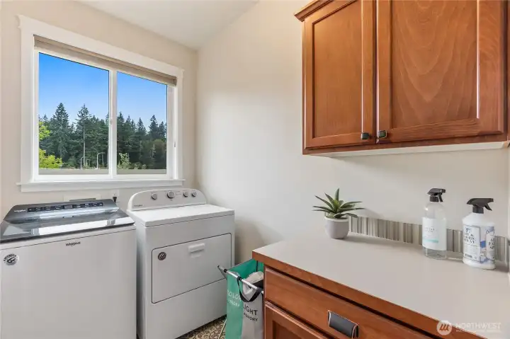 The laundry room provides ample storage with lovely maple cabinetry, a folding counter and a view over the open space next door.
