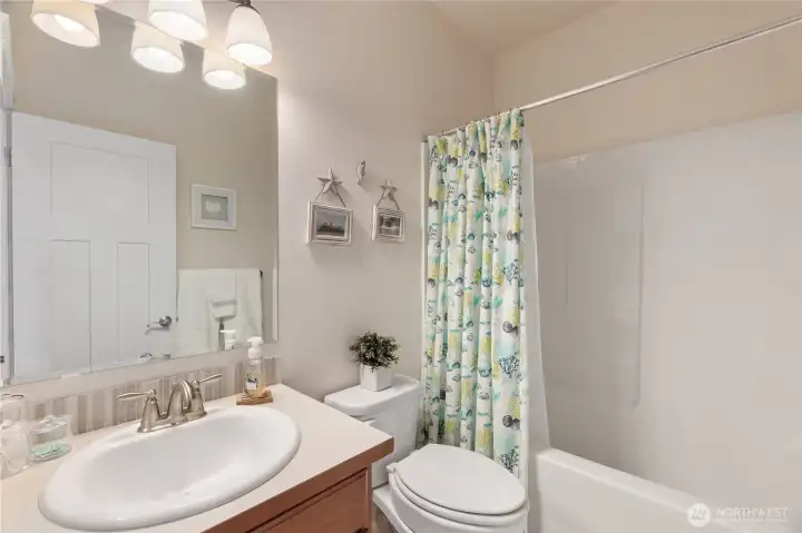 The hall bath has tall ceilings, a neutral color palette and a tub/shower combination.