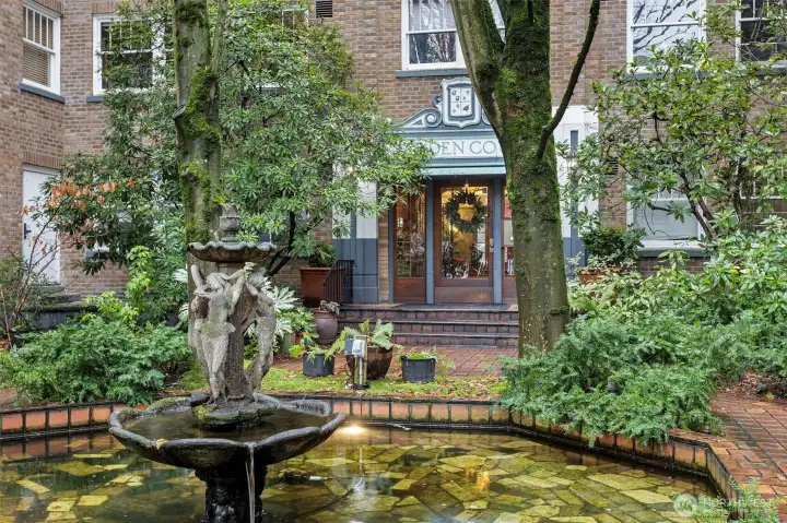 Garden Court’s central fountain and brick-lined courtyard create a serene, storybook welcome—framed by mature trees, lush plantings, and timeless architectural detail.