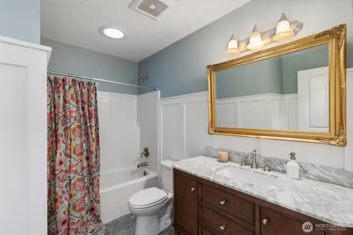 Charming hall bathroom with custom vanity, trim and tile floors.