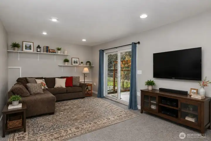 This AI digitally staged photo demonstrates part of the family room downstairs. Sellers have just move their furniture from the home.