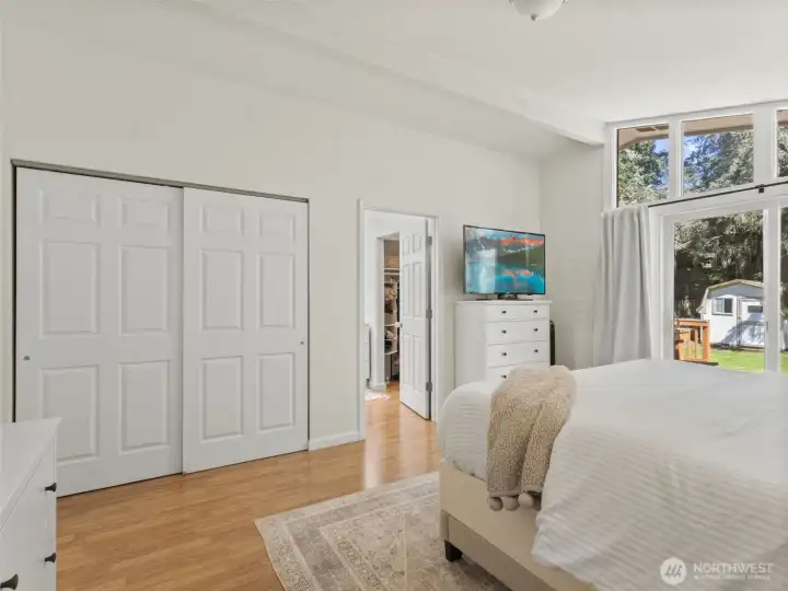 Another view of primary suite with two closets. One with double doors at left and a walk-in closet through the primary bathroom.