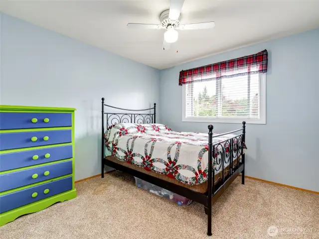 Guest bedroom with ceiling fan and wall-to-wall carpet.
