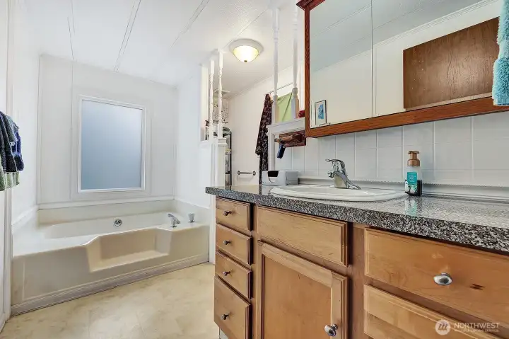 Private, bath off the primary bedroom. Single sink vanity with drawers and cabinets for all your bath necessities. Take a bubble bath an relax in the garden tub. Privacy half wall for the commode area.