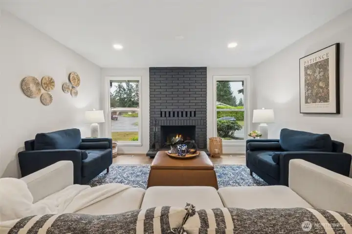 A bold accent fireplace anchors the living room with style and character, while the side windows wash the space in natural light. This combination creates a bright, cozy atmosphere that enhances the room’s open and welcoming feel.
