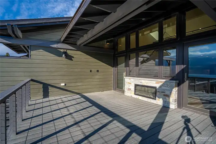 Indoor outdoor living with the fireplace and twin doors opening to the deck with two-side fireplace for indoor and outdoor enjoyment.