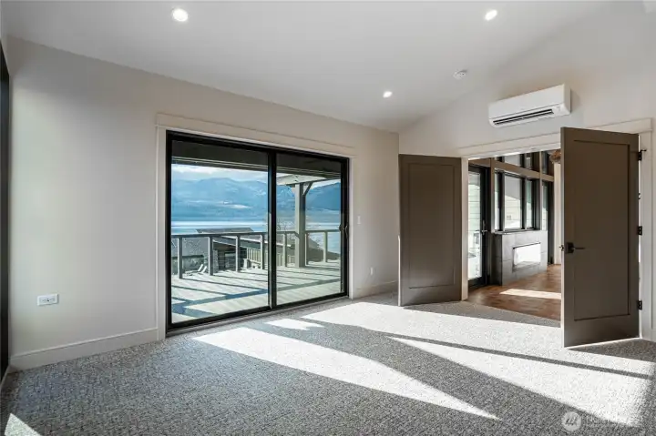 Primary bedroom with large glass sliding door opens to the deck overlooking the community pool.