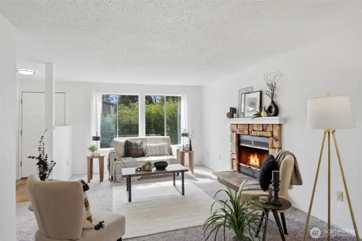 Welcoming living room with cozy fireplace and abundant natural light, a perfect space to relax or entertain right off the entry.