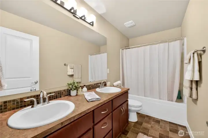 Main bathroom features double sinks, tile backsplash, and generous cabinet and counter space for added convenience.