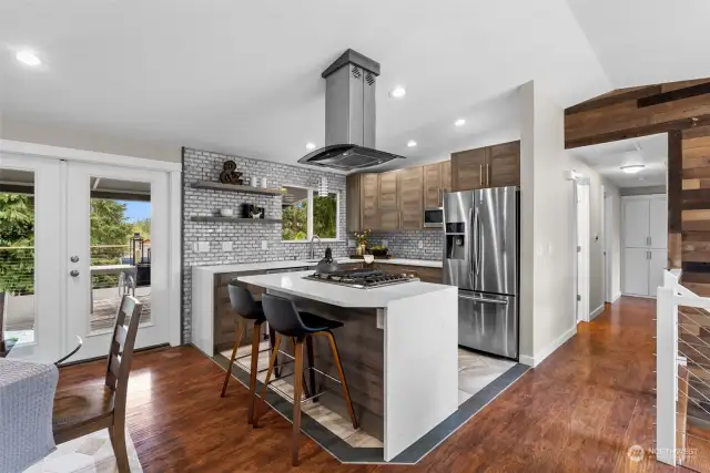 The upper level will have you mesmerized at every turn.  The homeowner embellished the kitchen walls with contemporary tile to blend seamlessly with the stainless steel appliances.  Floating wood shelves are the perfect touch to highlight this beautiful space.
