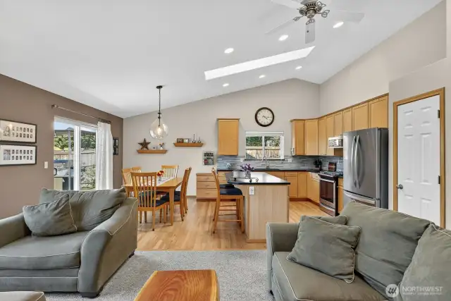 Looking from the family room towards the kitchen. There are vaulted ceilings, ceiling fan, & can lighting.