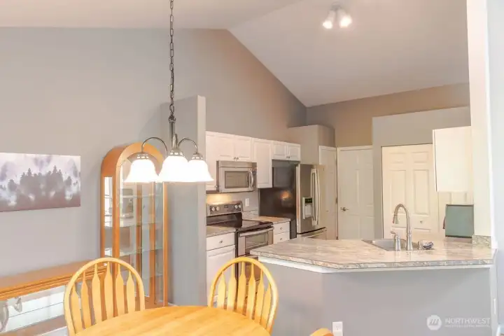 View from the dining room to the kitchen featuring pantry & vaulted ceilings.
