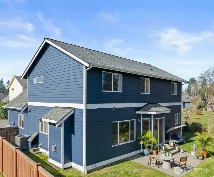 Back yard with patio. Heat pump on side of home along with pet door with stairs that are access via the laundry room. (photo virtually staged)