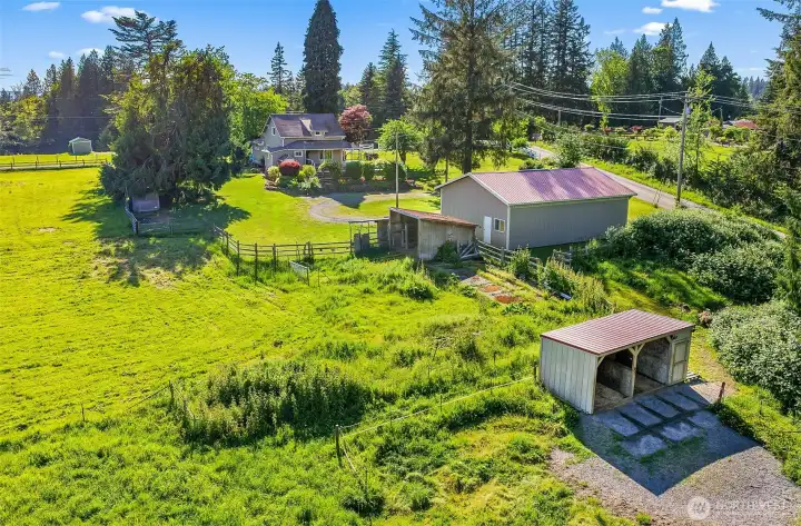 Run-in barn with attached hay/tack stall, additional livestock shelter to the left of the shop, cross fenced pastures.
