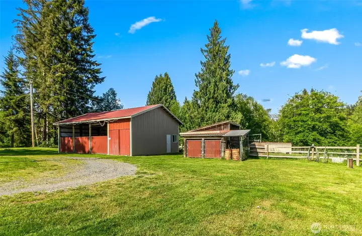 30x40 shop with the far right bay fully enclosed/insulated.  Misc storage shed on the right with a lawn mower shelter attached, livestock stall behind and then 2 stall run-in barn in the background.  Circular drive with lots of extra parking in this grass area leading up to the fenced pasture.