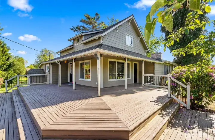 Large deck, partially covered.  Front door to the left leading into the kitchen and the side door on the right leads to the living room.  Downstairs basement exterior access is there on the left seen behind the deck railing.