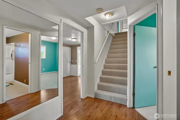 Main level hallway, brand new carpeted stairs leading up to 2 bedrooms and the 3/4 bathroom, door on right is a bedroom, thru the mirror on left you can see the reflection to the main full bath and behind the camera is the primary bedroom.