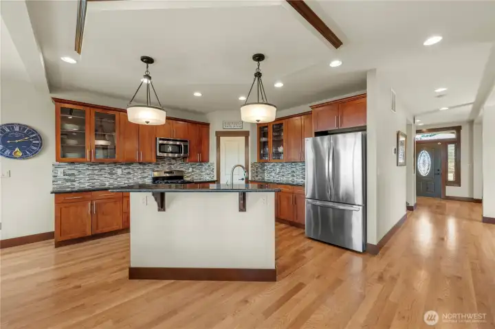 A kitchen designed for gathering, featuring granite slab countertops, custom cabinetry, and stainless steel appliances.