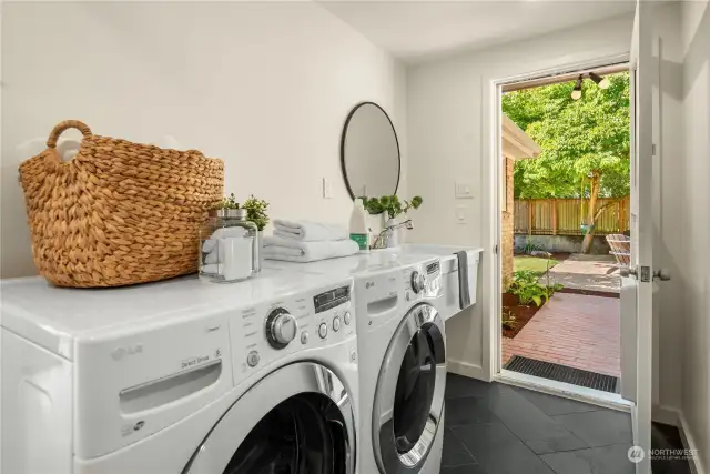 This oversized laundry room has a laundry sink, tiled floors and doubles as a mud room leading to the backyard.