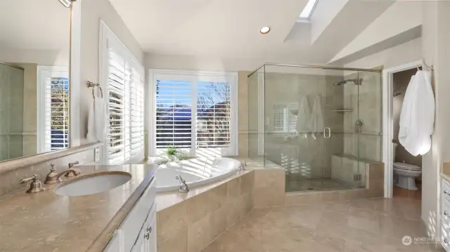 Primary bath boasts a large jetted soaking tub, frameless glass walk-in shower, makeup station (not pictured) all with limestone accents.