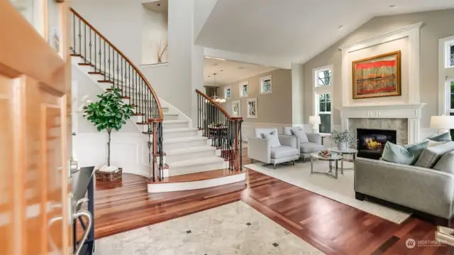 Gorgeous 2-story entry showcasing Brazilian cherry hardwood floors, marble tile inlay, and dramatic curved staircase.