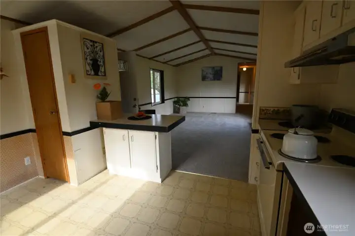 Open concept kitchen and living. 2-sided storage to the left is 1/2 shelving for pantry, 1/2 coat closet near door.