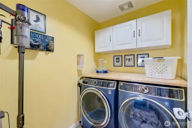 A utility room with cabinetry and folding counter.